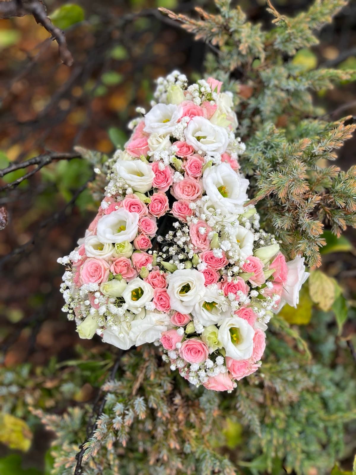 Aranjament floral în formă de inimă cu trandafiri roz și albi pe ramuri de brad