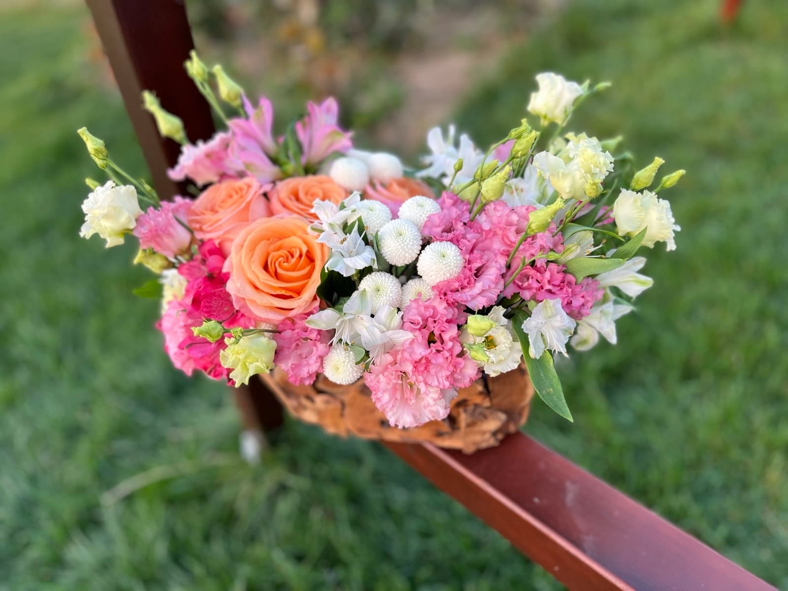 Aranjament floral colorat pe o buturugă de lemn, într-o livadă